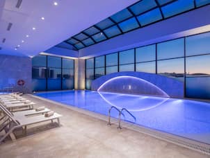  Lounge Seating by Indoor Pool With Large Windows, Blue Lighting, and Sunset View