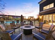 Outdoor patio area with lounge chairs surrounding firepit at sunset