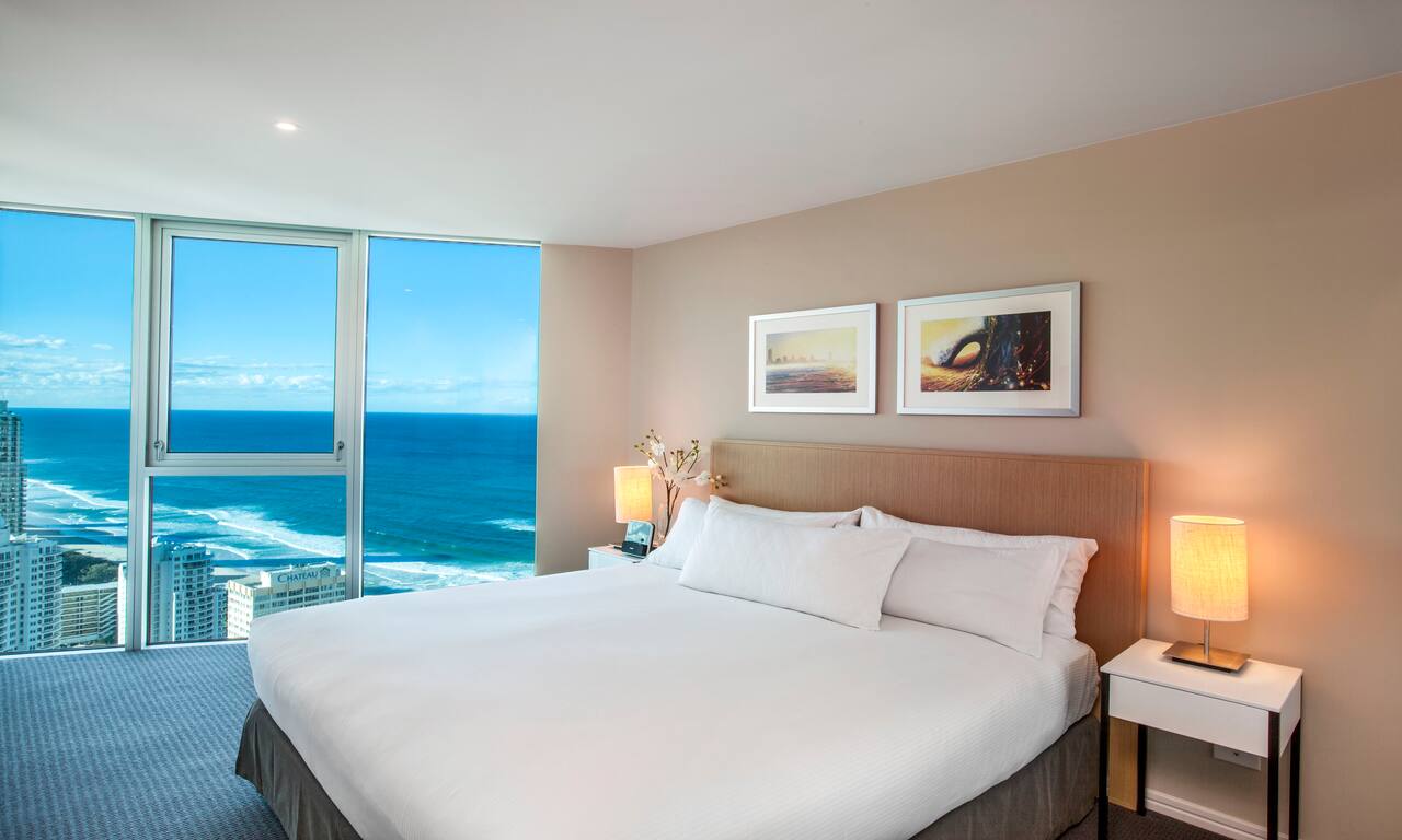   Bed in Guest Room with Large Window Overlooking Ocean 