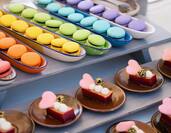 A table displaying multicolored sweet treats including macarons and chocolate with red hearts on top.