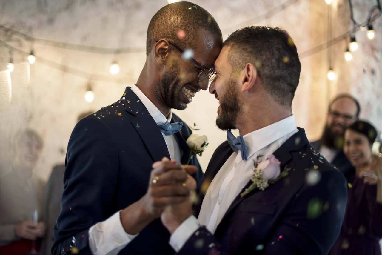 Two grooms dancing together at wedding reception