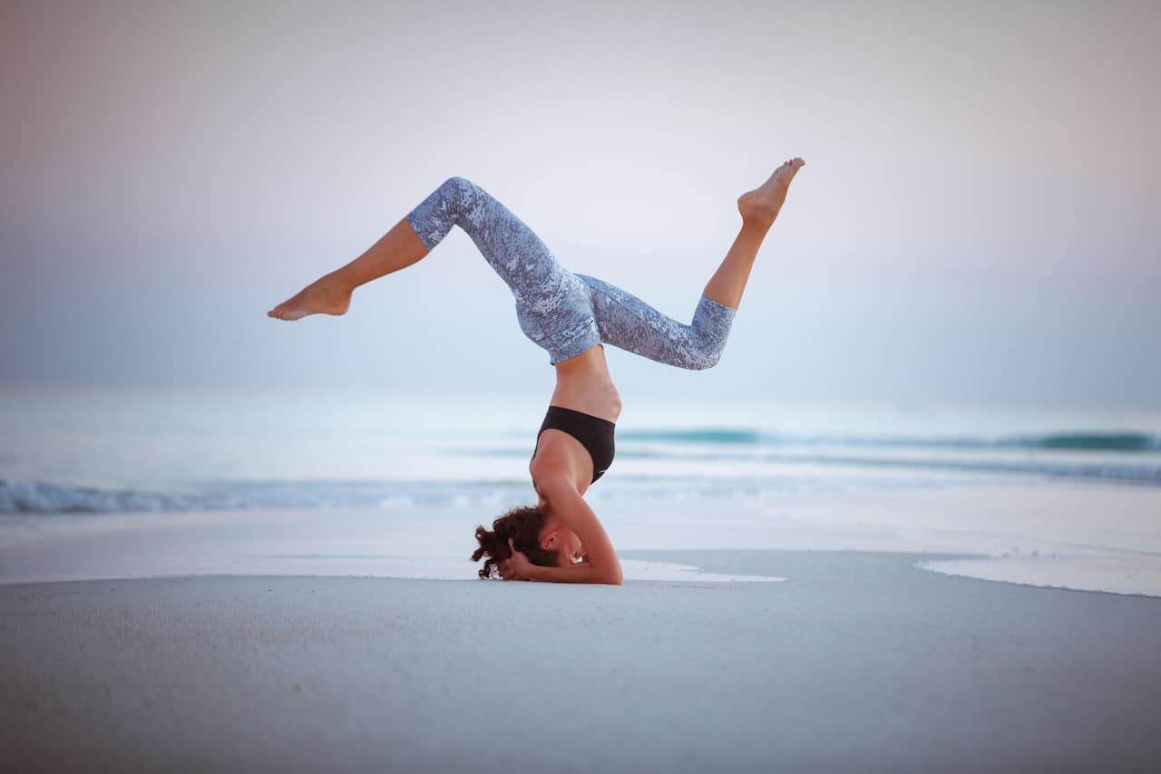 Woman doing a headstand on the beach