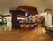 Panoramic View of Counter Seating at Well-Stocked Bar, TV, Tables and Armchairs in Bar Lounge