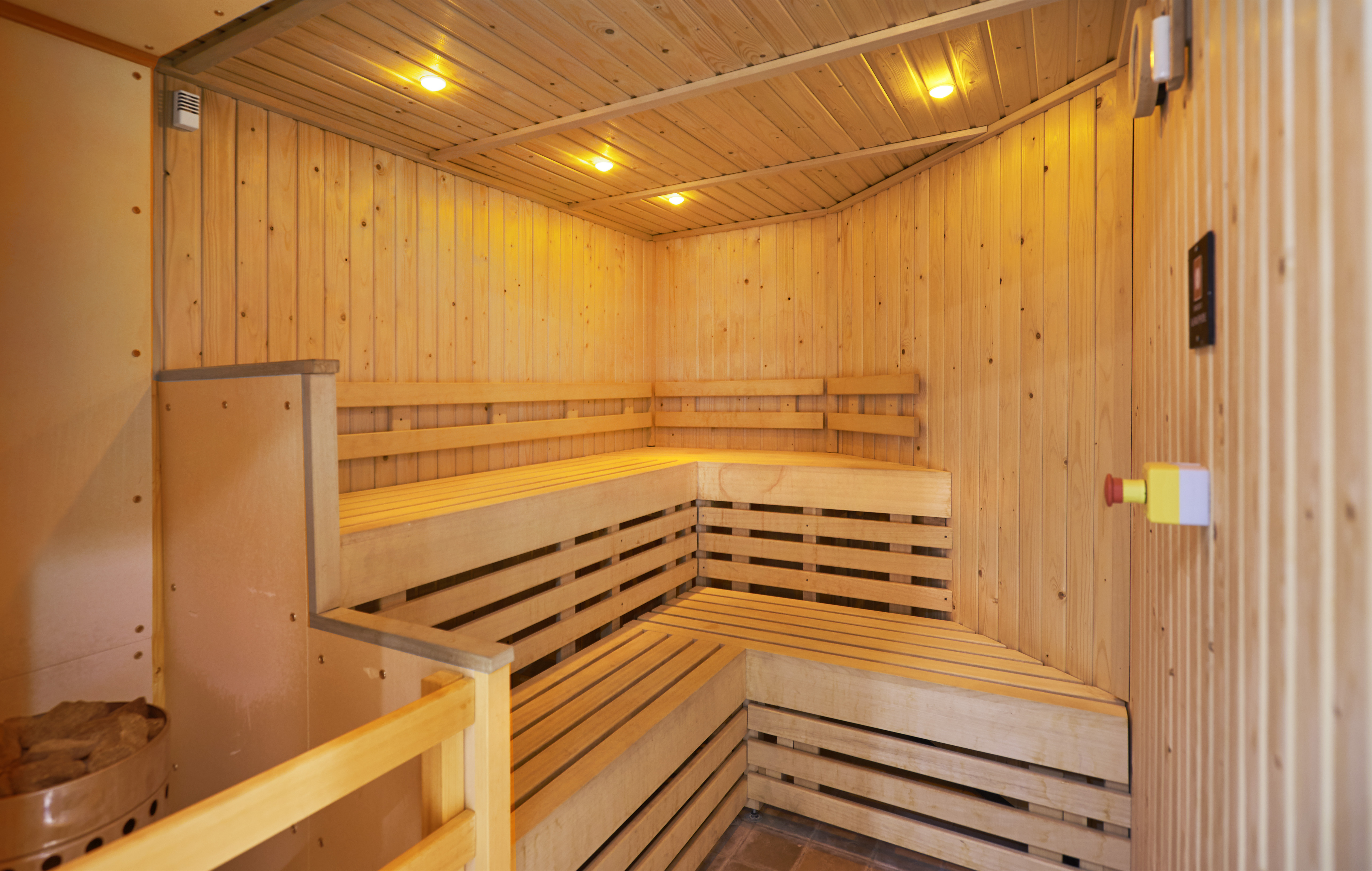  Illuminated Wooden Sauna Interior With Bench Seating and Heater in Corner