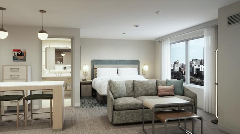 Example rendering of studio suite with bed, sofa, bathroom, and table with two chairs