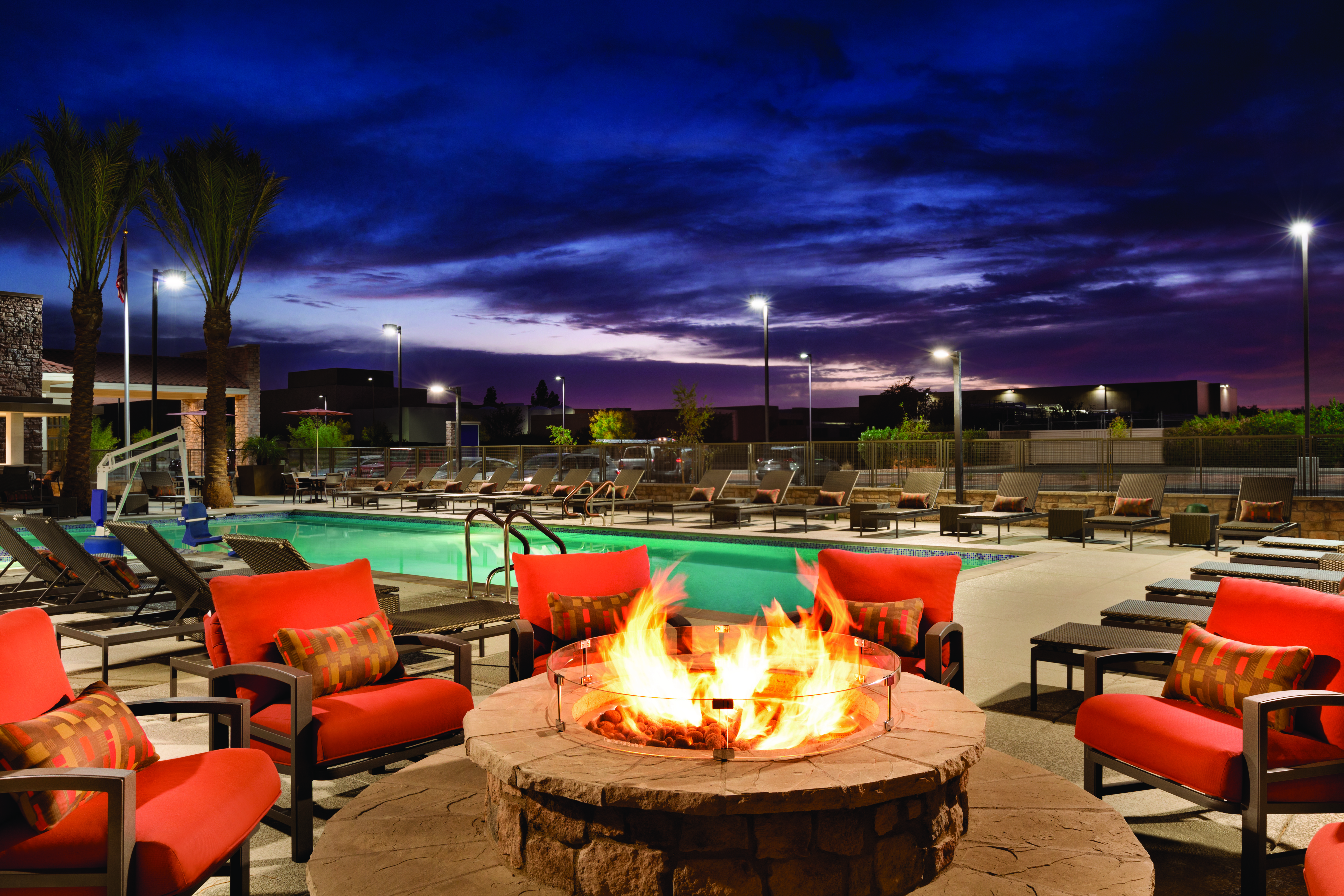 Outdoor Firepit with Armchairs next to Outdoor Pool at Dusk