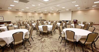 Spacious Ballroom Area with Round Tables, Chairs and Projector Screen