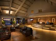 Illuminated Lobby With Lounge Seating, Sunset View of Ocean, and Two Staff Members Behind Front Desk
