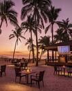 Sunset View of Candlelit Tables and Chairs Surrounded by Sand and Palm Trees at Tavu Grill
