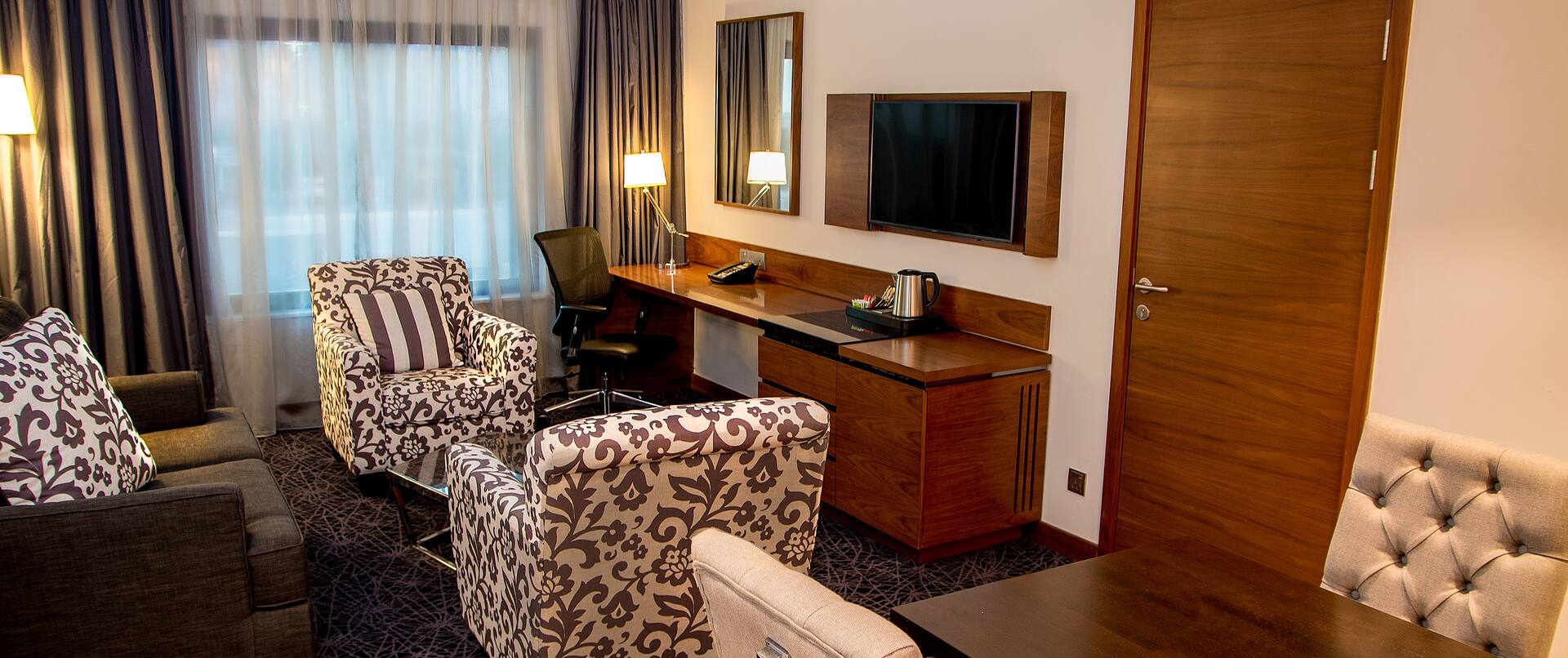 Guest Suite Lounge Area with Armchairs, Sofa, Work Desk and Wall Mounted HDTV