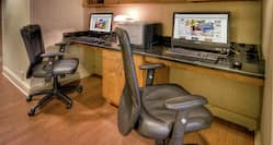 Two work stations in business center with computer set up and chair