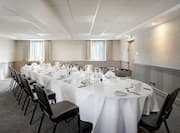 Windows With Sheer Drapes, 14 Place Settings on Long Table With White Linens Set Up for Private Dinner in Meeting Space