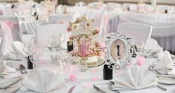 Place Settings, Wine Glasses, Decrorative Frame and Wedding Favors on Round Tables With White Linens Decorated for Wedding Reception