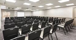 Enbourne Suite Arranged Theater Style With Rows of Chairs Facing Projector Screen and Window With Sheer Drapes