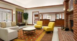 Soft Seating and Table Around Fireplace in Lobby Lounge Area With View of Front Desk