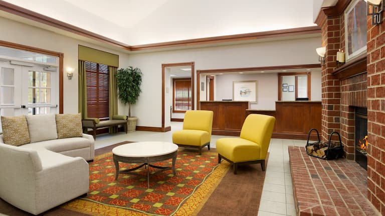 Soft Seating and Table Around Fireplace in Lobby Lounge Area With View of Front Desk