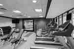 Fitness Center With Cardio Equipment Facing Windows, Weight Benches, Free Weights, TV, Red Exercise Ball, Large Mirrored Wall and Weight Balls