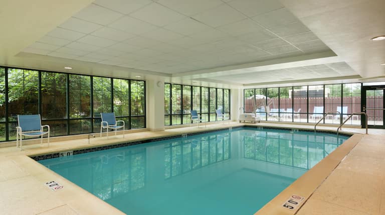 Four Blue Chairs by Large Windows of Indoor Pool