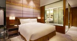 King Deluxe Room with bed and transparent window view of bathroom and shower
