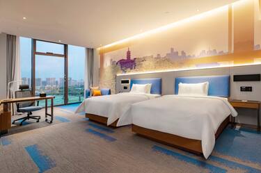 two twin beds with work desk and view of city