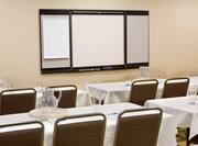 Detailed View of Conference Room With Classroom Tables and Chairs Facing Presentation Easel