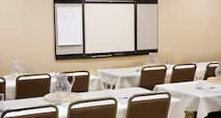 Detailed View of Conference Room With Classroom Tables and Chairs Facing Presentation Easel
