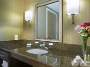 Detailed View of Brightly Lit Vanity Mirror, Sink, Fresh Towels, and Amenities
