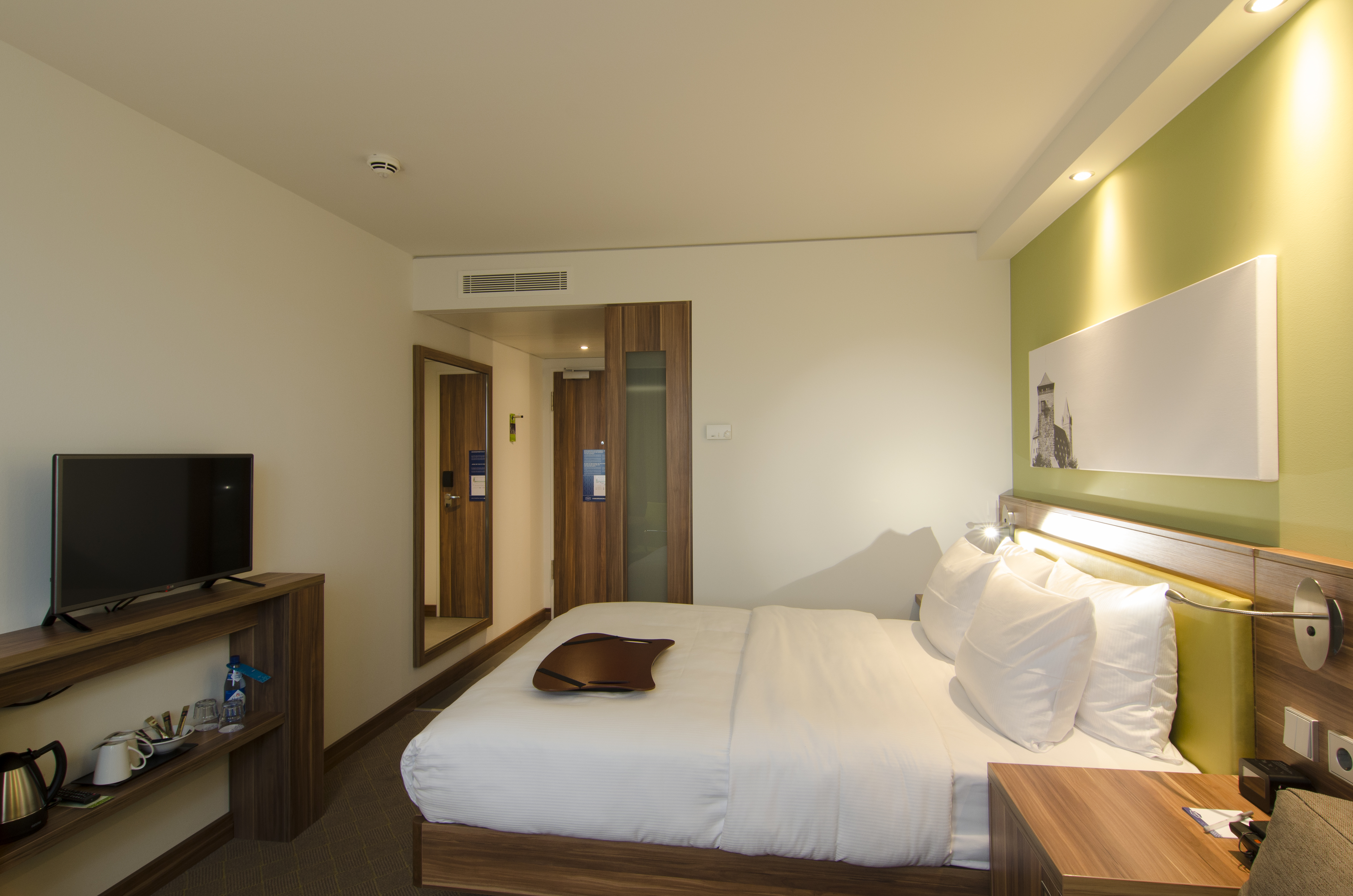 Schlafzimmer mit Queensize-Bett und Fernseher – Blick auf die Tür