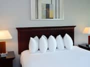 Wall Art, King Bed Between Two Bedside Tables With Illuminated Lamps in Guest Room
