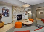 Fireplace Sitting Area With Wall Art, Round Table, Two Orange Ottomans, Floor Lamp and Two Sofas