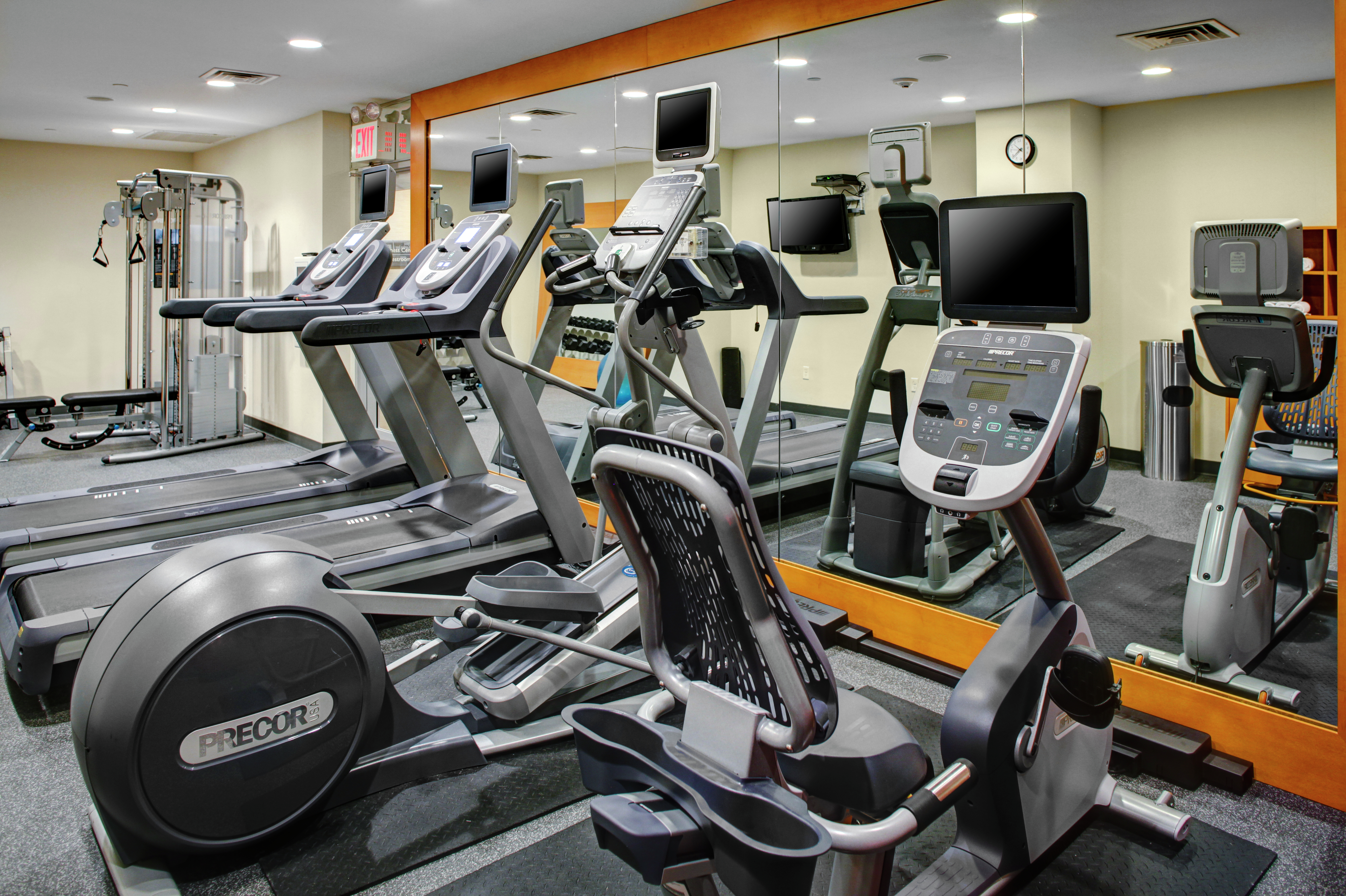 Fitness Center With TV, Weight Machine, Mirrored Wall, and Cardio Equipment, 