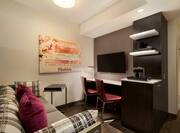 Guest Suite Lounge Area with Sofa, Work Desk, Wall Mounted HDTV and Coffee Machine