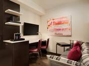 Guest Studio Lounge Area with Sofa, Work Desk, Wall Mounted HDTV and Coffee Machine
