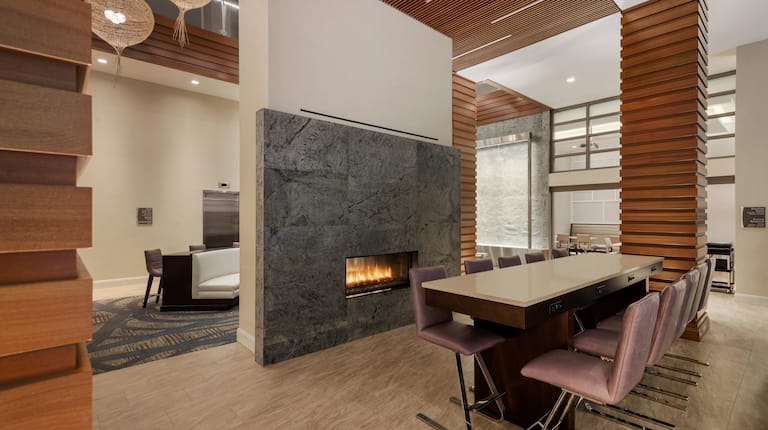 Lodge Area With Seating for Ten at Long Table by Fireplace, Large Windows and View of Soft Seating Behind Partition