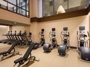 Fitness Center With Overheard Windows to Upstairs Lobby, Cardio Equipment, and Weight Benches
