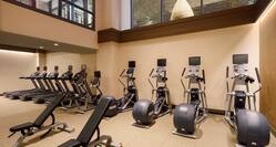 Fitness Center With Overheard Windows to Upstairs Lobby, Cardio Equipment, and Weight Benches