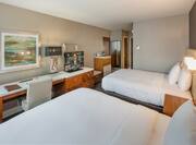 Two Queen Beds, Illuminated Lamp Above Bedside Tables, Wall Art Above Work Desk With Ergonomic Chair, HDTV, Hospitality Center, and Full Length Mirror in Guest Room