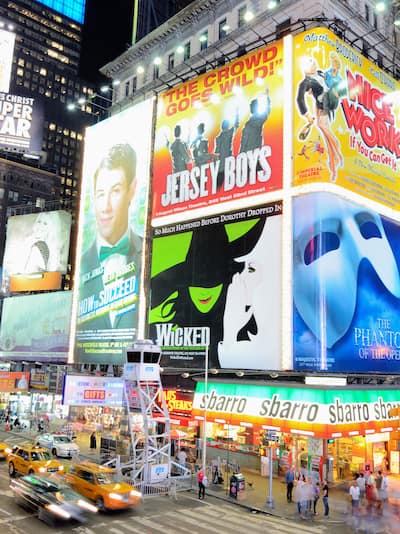 Street view of Broadway at night wiith billboards and yellow cabs