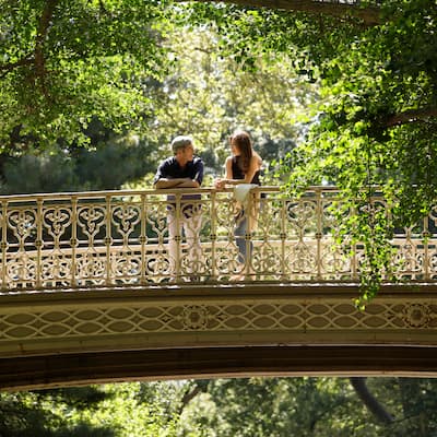 Two people standing on a Central Park bridge