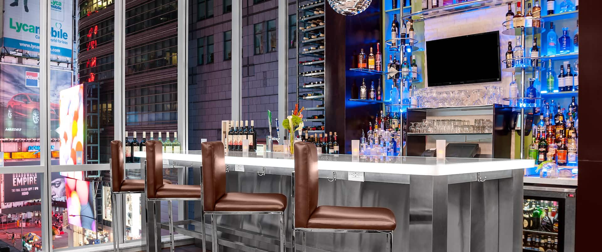 Lobby bar with barstools, bottles on shelves and city view from large window