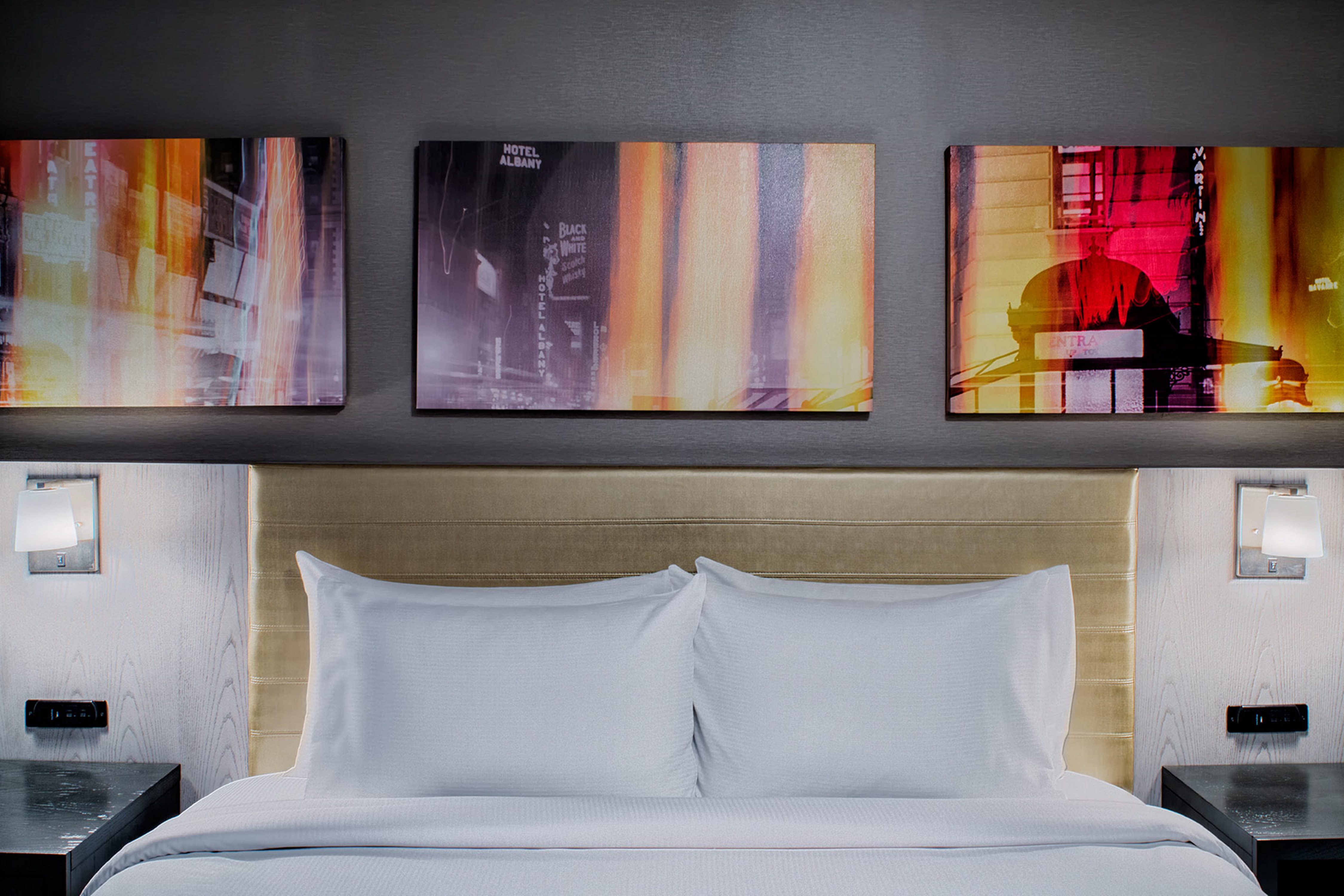 Wall Art Above King Bed, Illuminated Lamps, and Bedside Tables in Guest Room
