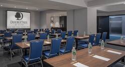 Classroom Setup in Meeting Room 1 With Entry, Refreshment Area, Tables and Chairs Facing Presentation Screen