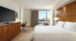 Spacious guest room featuring comfortable king bed, TV, work desk, and city view.