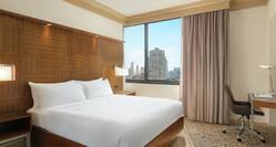 Spacious private bedroom in suite featuring comfortable king bed and stunning city view.