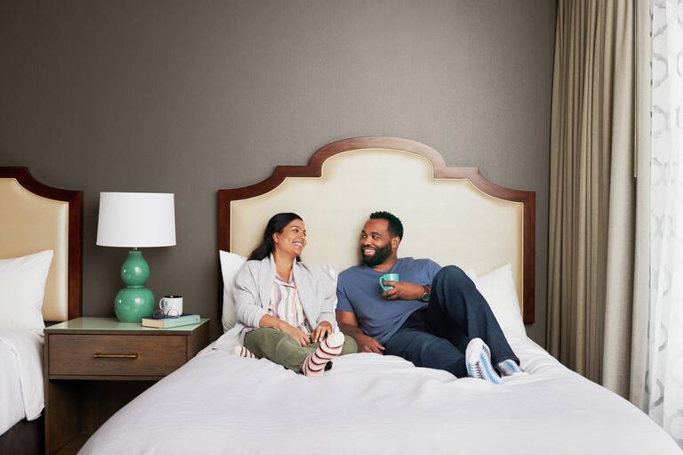 Couple sitting on a bed in a double beds room