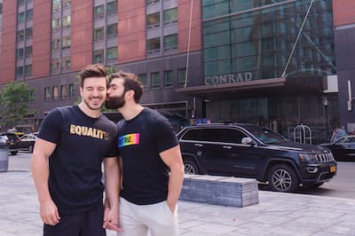 LGBTQ+ couple holding hands outside Conrad New York Downtown.