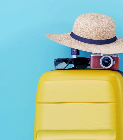 Hat, sunglasses, camera atop a suitcase