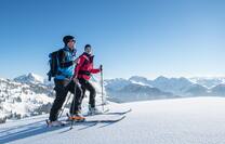 A man and woman in ski wear at the top of mountain. 