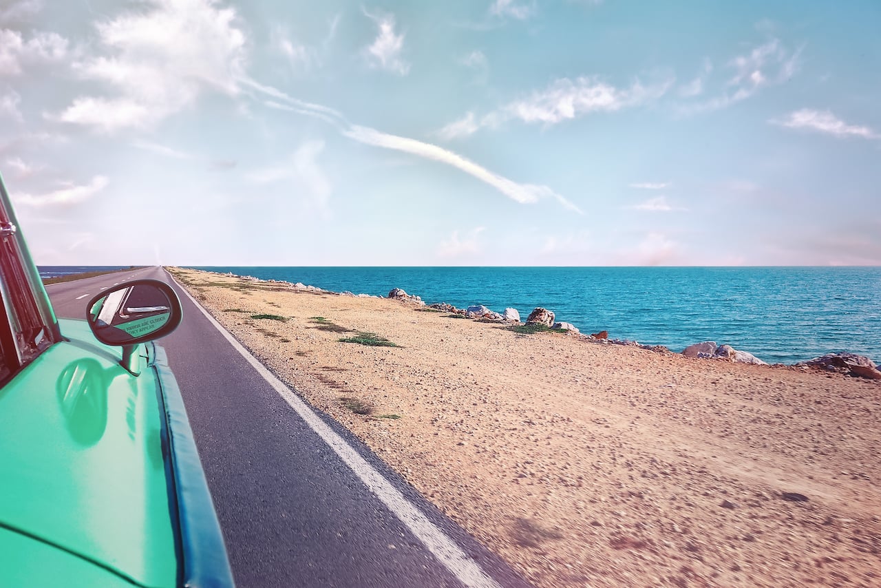 View of the ocean from the back seat of a classic car