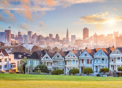 A row of period houses with the San Francisco skyline in the background.